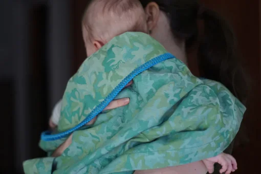 baba zöld takaróba bugyolálva anyukája kezében