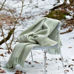 skandináv stílusú pléd havas erdőben székre terítve
