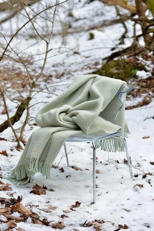 skandináv stílusú pléd havas erdőben székre terítve