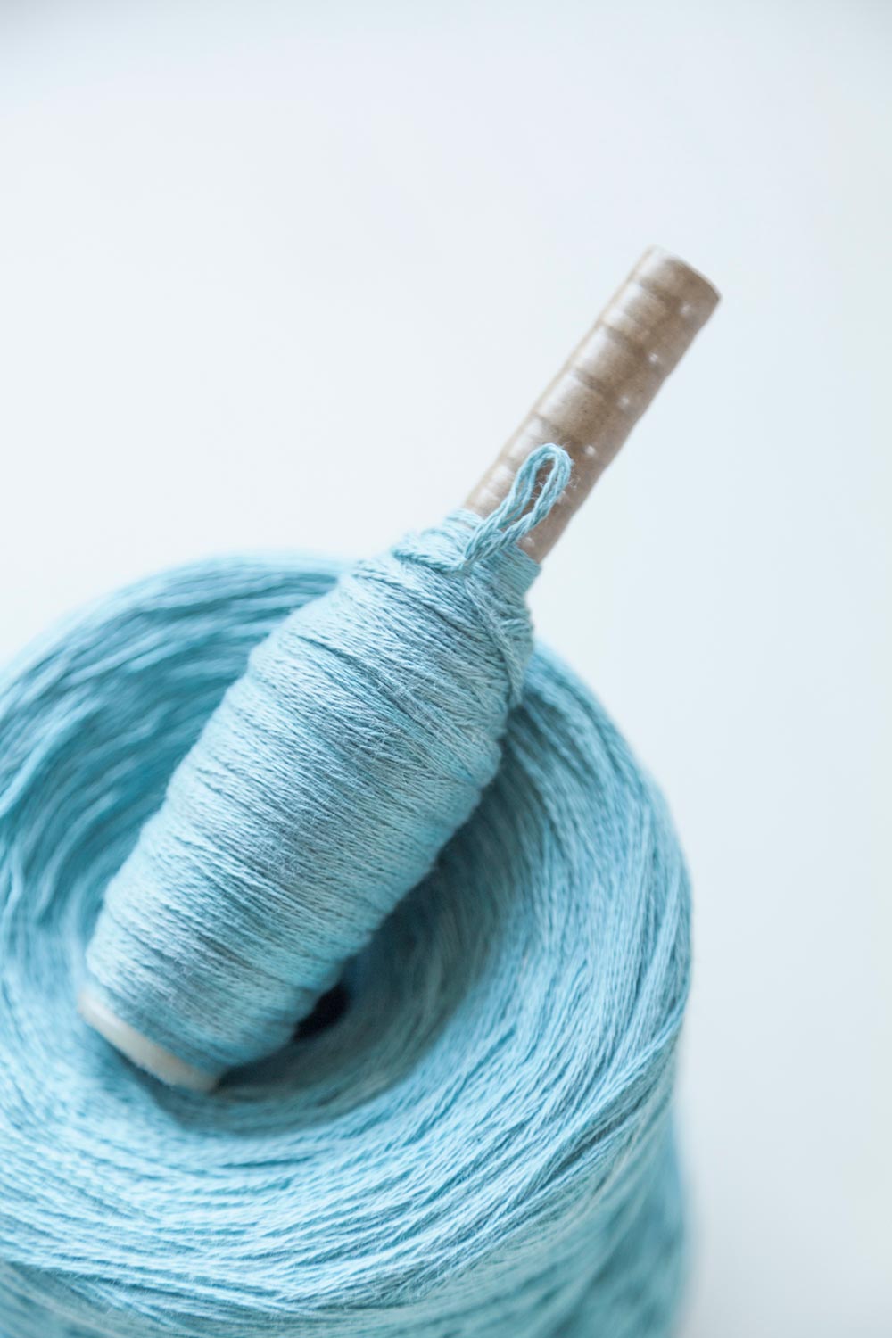 a blue hand dyed cotton yarn ball and a weaving pirn