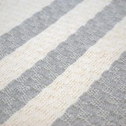 detail of a handwoven cushion with white and grey stripes